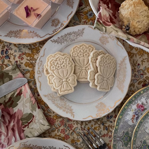 Flower shaped cookies on a plate surrounded by other plates and pastries